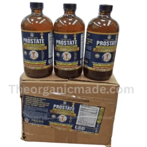 A Clean photograph showing three large, amber glass bottles of "Complete Prostate Gland Health Formula" with black caps, positioned side-by-side on top of a sealed cardboard box. Each bottle features a detailed blue and white label with the product name and key health claims. The cardboard box also has a larger, full label affixed to the front, displaying the supplement facts panel and product description. The image is taken from a three-quarter view, slightly elevated. A large, transparent watermark text "Theorganicmade.com" overlays the lower half of the image. The bottles are filled with a liquid supplement. The packaging looks secure and professional.