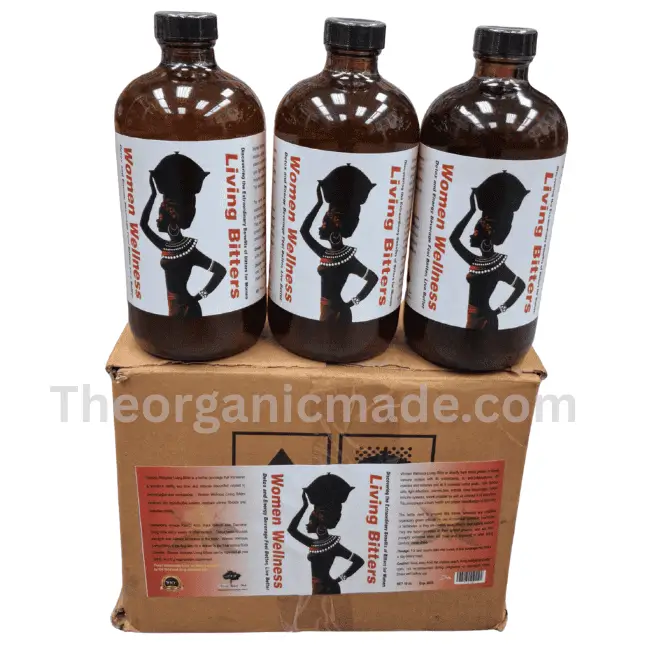 Women Wellness Living Bitters 16oz - (Wholesale) 1 A three-quarter view studio product photograph of a shipping box with three amber glass bottles of "Living Bitters" stacked on top. The box and each bottle feature a white label with a silhouette of an African woman in a headdress and traditional attire carrying a basket on her head. The text "Women Wellness Living Bitters" is prominent, with "Women Wellness" on the left and "Living Bitters" on the right. The box label also includes dense nutritional information and ingredient lists. A large watermarked text "www.theorganicmade.com" overlays the image.