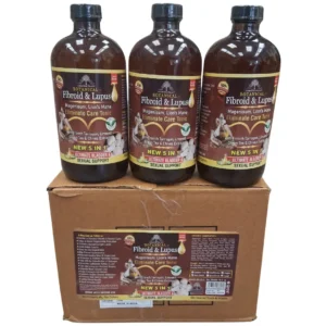 A photograph of three 16oz amber glass bottles of "Botanical Fibroid & Lupus" Eliminate Care Tonic stacked on a brown cardboard shipping box against a white background. The full labels of the bottles are visible, featuring the Essential Palace logo and a comprehensive list of ingredients like Magnesium, Lion's Mane, French Tarragon, and Linseed. The complex case label on the box detailed health benefits and ingredients.