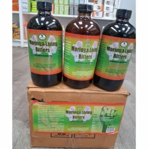 three dark glass bottles of Moringa Living Bitters are centered on a light wood surface. It is flanked by two framed diagrams connected by red arrows. The left diagram, 'KEY BENEFITS', highlights 'Support Detoxification', 'Boost Energy', 'Anti-inflammatory', and 'Rich in Antioxidants'. The right diagram, 'NATURAL INGREDIENTS', lists 'Natural Moringa', 'Bitter Gourd', 'Cinnamon', 'Garlic', 'Blackseed', and 'Dandelion'. Below the infographic, an arrangement of raw ingredients is shown: a large bunch of fresh dandelion greens with roots, two fresh bitter gourd vegetables, and several cinnamon sticks. The graphic features green and red text and accents. Header text at the top reads 'EMPOWER YOUR WELL-BEING' and 'MORINGA VITALITY BLEND: PURIFY & RECHARGE'. The dark bar at the bottom says 'REVITALIZE YOUR ESSENCE • THRIVE VIBRANTLY'.