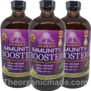 A detailed product photograph and marketing graphic featuring a large amber glass bottle of Essential Palace Organic Immunity Booster living bitters with blacl elderberry 16oz. The product label is rich purple and gold, detailed with illustrations of clusters of Black Elderberry and green leaves. The label text prominently states "Essential Palace ORGANIC IMMUNITY BOOSTER" in large white and gold letters, with "with Black Elderberry, Echinacea & Thyme" specified below. Three key benefit statements—"Helps with Cough", "Helps with Fever", and "Helps with Flu"—are listed above "VITAL ENERGY & STRENGTH". Two trust badges ("Essential Blessing" and "100% SATISFACTION") are prominent. To the right of the bottle, against a stark white background with a green header banner reading "RELIEF FOR:", is a bold, multi-point bulleted list of 9 health benefits: "Gut Health Support", "Helps with COUGH", "Fever & FLU", "Give Vital Energy & Strength", "LIBIDO BOOSTER", "ANTIOXIDANTS", "Reduces inflammation", "Detoxify", and "Rich in Minerals & Vitamins". The top-left corner features "THE ORGANIC MADE: NATURAL & HEALTHY" circular seal. The bottom center displays the website URL "www.theorganicmade.com" in grey text. pack of 3